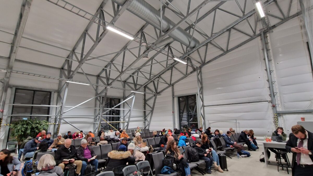 Interior of a well-lit hangar filled with people waiting. Hallgruppen has created a comfortable and functional environment for waiting passengers.