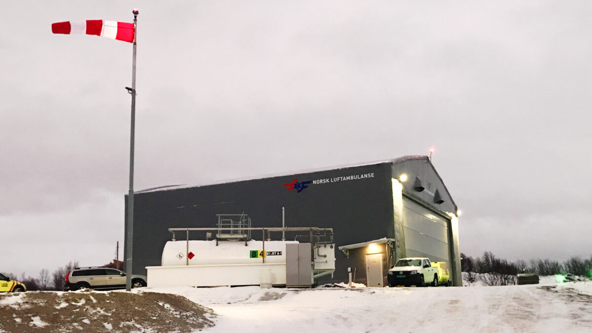 A hangar in a winter setting with a Norwegian air ambulance helicopter on the landing pad. Hallgruppen designed this facility to function optimally in cold conditions.