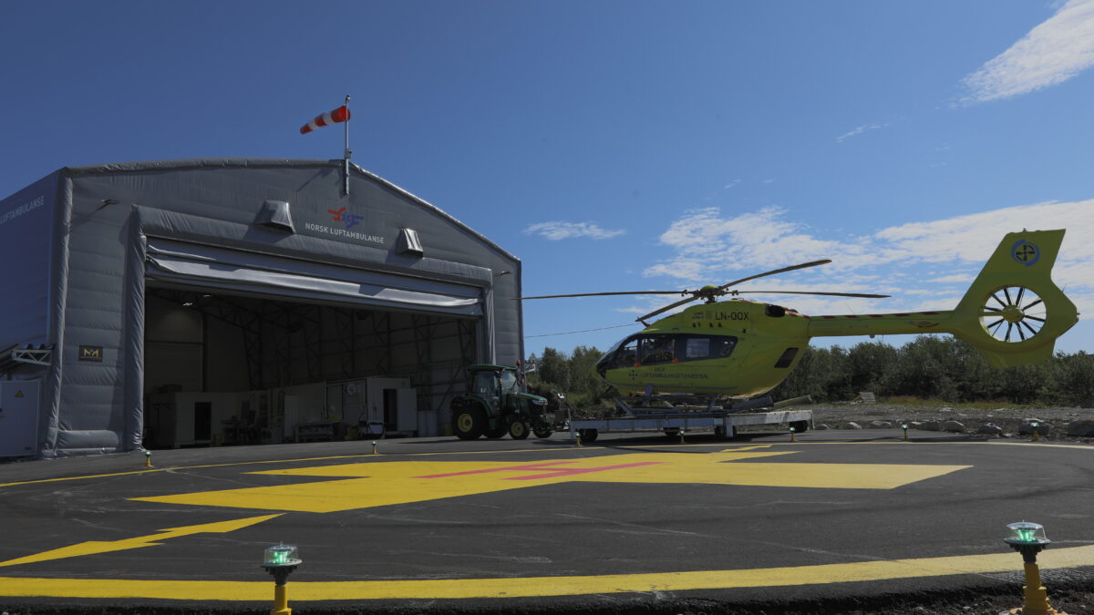 A helicopter is parked in front of a hangar, ready for the next mission. This hangar, built by Hallgruppen, provides a safe and secure space for air ambulance operations.