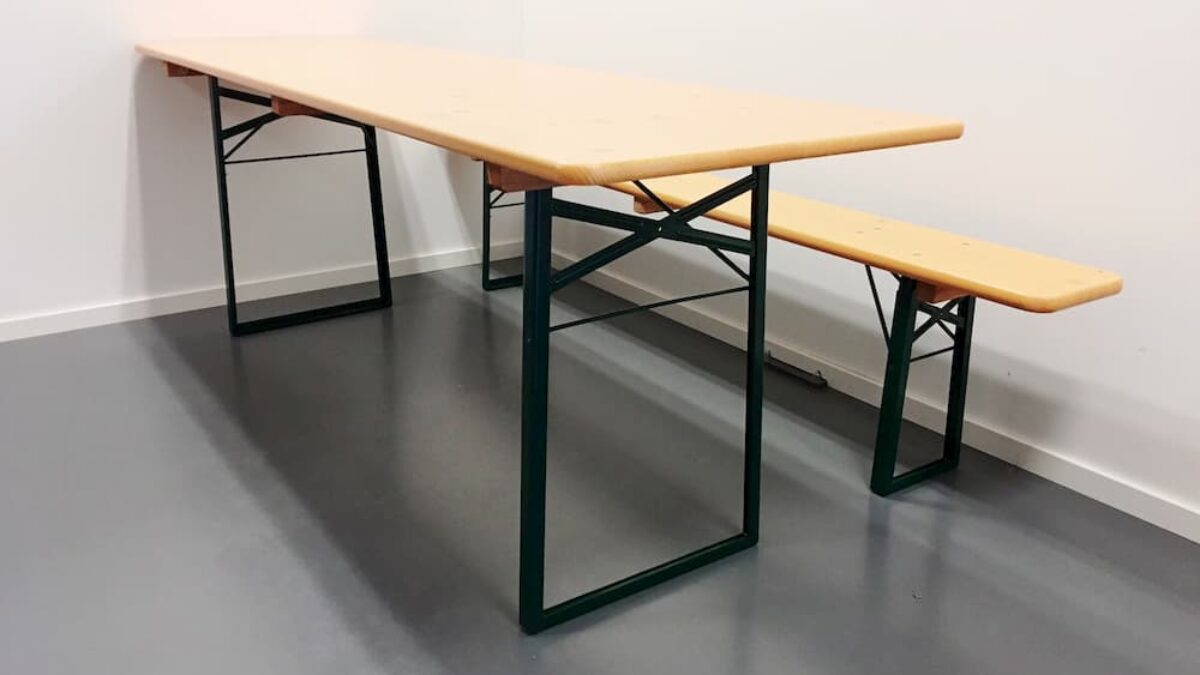 An orange table and bench set arranged indoors on a gray floor. The furniture is sturdy and provided by Hallgruppen.